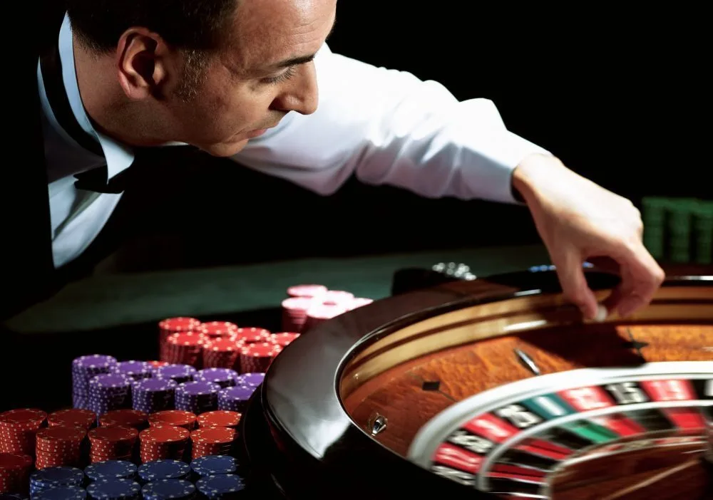 Dealer placing the ball into a roulette wheel.