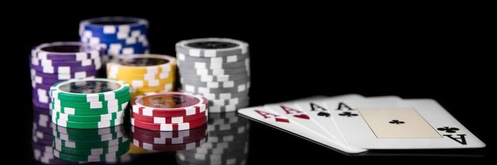 Poker chips sitting next to four aces(playing cards).