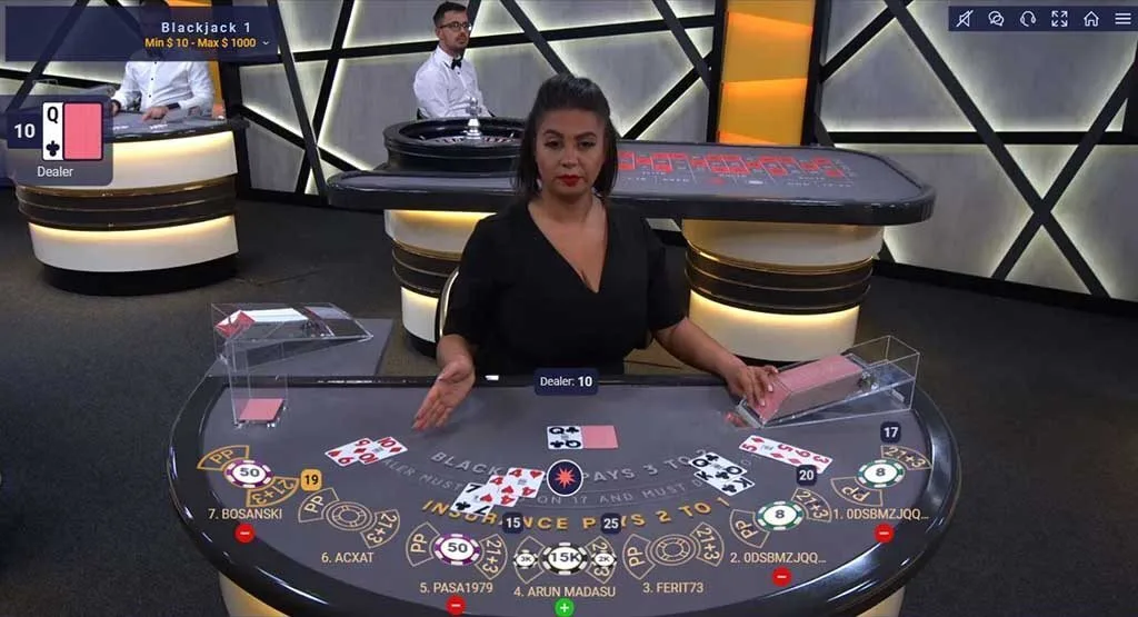 Female dealer sitting at blackjack table with 4 hands dealt.